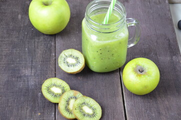 Green healthy smoothie in glass jar: banana, kiwi, green apple on rustic background