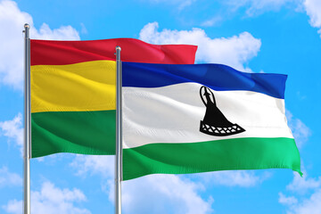 Lesotho and Bolivia national flag waving in the windy deep blue sky. Diplomacy and international relations concept.