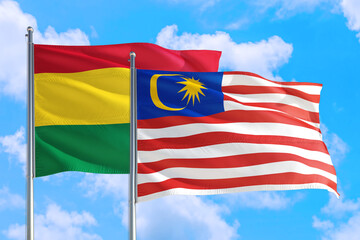 Malaysia and Bolivia national flag waving in the windy deep blue sky. Diplomacy and international relations concept.