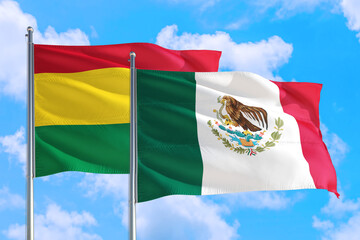 Mexico and Bolivia national flag waving in the windy deep blue sky. Diplomacy and international relations concept.