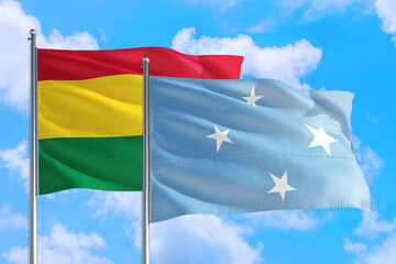 Micronesia and Bolivia national flag waving in the windy deep blue sky. Diplomacy and international relations concept.