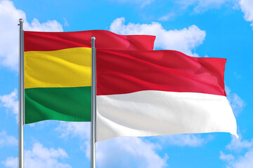 Monaco and Bolivia national flag waving in the windy deep blue sky. Diplomacy and international relations concept.