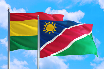 Namibia and Bolivia national flag waving in the windy deep blue sky. Diplomacy and international relations concept.