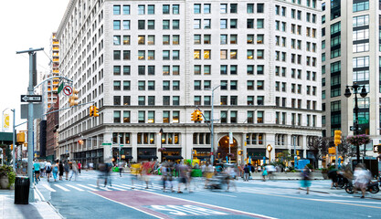 Crowds of people in motion walking across the busy intersection of 23rd Street and Broadway in...
