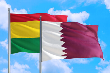 Qatar and Bolivia national flag waving in the windy deep blue sky. Diplomacy and international relations concept.