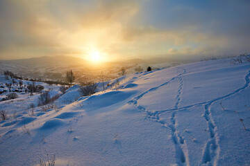 January landscape in the mountains. The sun rises from behind the mountain in winter
