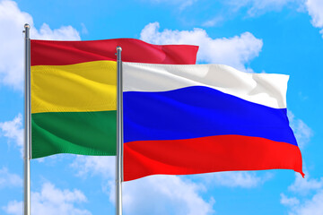 Russia and Bolivia national flag waving in the windy deep blue sky. Diplomacy and international relations concept.