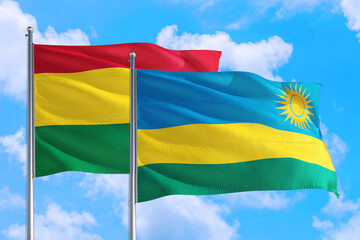 Rwanda and Bolivia national flag waving in the windy deep blue sky. Diplomacy and international relations concept.