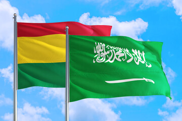 Saudi Arabia and Bolivia national flag waving in the windy deep blue sky. Diplomacy and international relations concept.