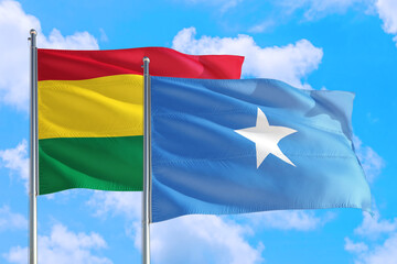 Somalia and Bolivia national flag waving in the windy deep blue sky. Diplomacy and international relations concept.