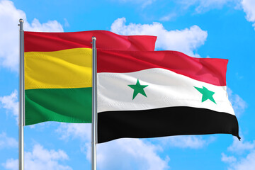 Syria and Bolivia national flag waving in the windy deep blue sky. Diplomacy and international relations concept.