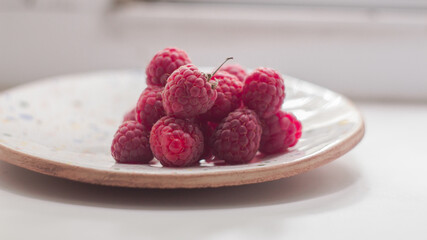 Ripe juicy raspberries lies on a plate. Ripe organic raspberries close-up.