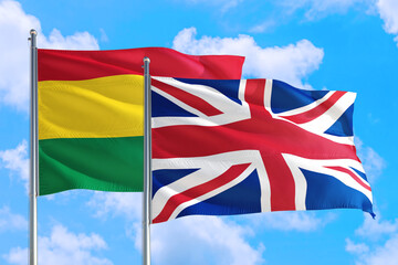 United Kingdom and Bolivia national flag waving in the windy deep blue sky. Diplomacy and international relations concept.