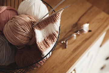 Yarn balls and knitting needles in metal basket on wooden table, closeup with space for text....