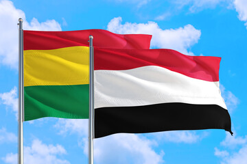 Yemen and Bolivia national flag waving in the windy deep blue sky. Diplomacy and international relations concept.