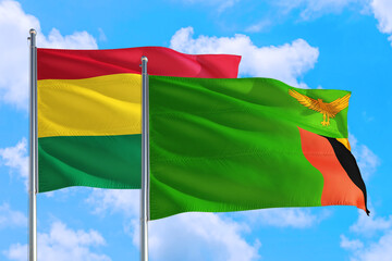 Zambia and Bolivia national flag waving in the windy deep blue sky. Diplomacy and international relations concept.