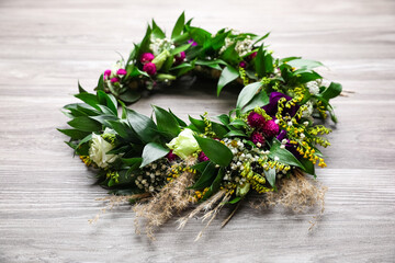 Beautiful wreath made of flowers and leaves on wooden table