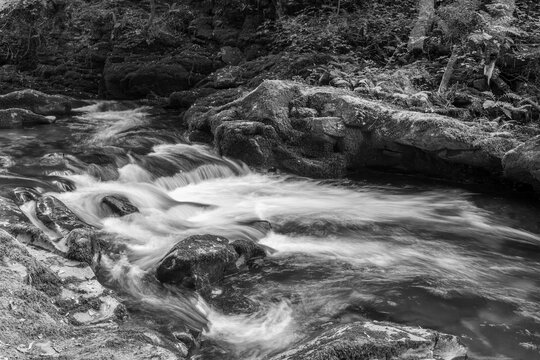 Long exposure of a waterfall on the East Lyn river flowing through the woods at Watersmeet in Exmoor National Park