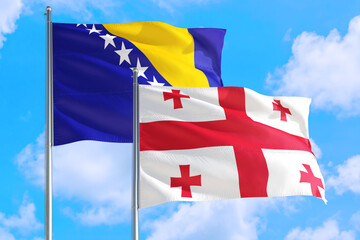 Georgia and Bosnia Herzegovina national flag waving in the windy deep blue sky. Diplomacy and international relations concept.