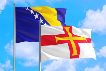 Guernsey and Bosnia Herzegovina national flag waving in the windy deep blue sky. Diplomacy and international relations concept.