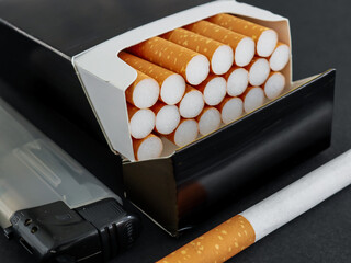 cigarettes in a box.
Cigarettes in a black box and a gray lighter, very close-up side view.