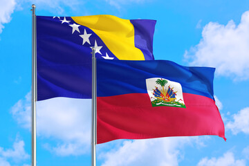 Haiti and Bosnia Herzegovina national flag waving in the windy deep blue sky. Diplomacy and international relations concept.
