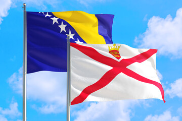 Jersey and Bosnia Herzegovina national flag waving in the windy deep blue sky. Diplomacy and international relations concept.
