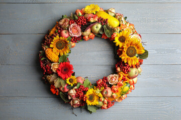 Beautiful autumnal wreath with flowers, berries and fruits on light grey wooden background, top view. Space for text