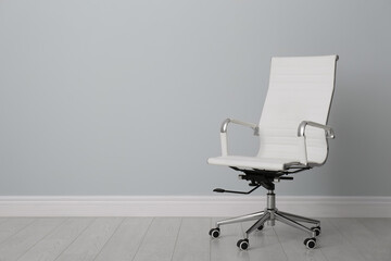 Comfortable office chair near light wall indoors. Space for text