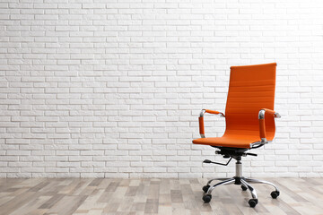 Comfortable office chair near white brick wall indoors. Space for text - obrazy, fototapety, plakaty
