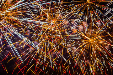 Vivid colorful fireworks on black background with red and golden sparks.