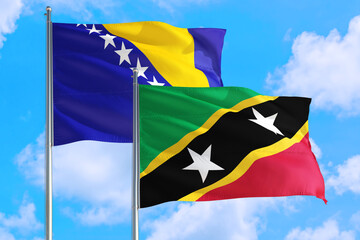 Saint Kitts And Nevis and Bosnia Herzegovina national flag waving in the windy deep blue sky. Diplomacy and international relations concept.