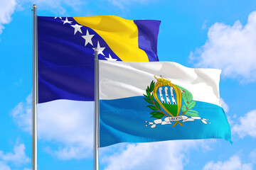 San Marino and Bosnia Herzegovina national flag waving in the windy deep blue sky. Diplomacy and...