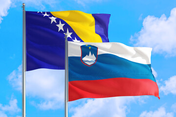 Slovenia and Bosnia Herzegovina national flag waving in the windy deep blue sky. Diplomacy and international relations concept.