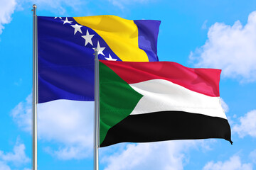 Sudan and Bosnia Herzegovina national flag waving in the windy deep blue sky. Diplomacy and international relations concept.