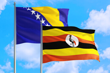 Uganda and Bosnia Herzegovina national flag waving in the windy deep blue sky. Diplomacy and international relations concept.