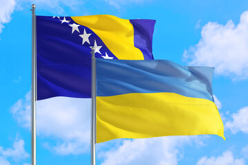 Ukraine and Bosnia Herzegovina national flag waving in the windy deep blue sky. Diplomacy and international relations concept.