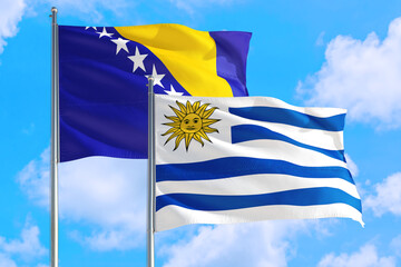 Uruguay and Bosnia Herzegovina national flag waving in the windy deep blue sky. Diplomacy and...