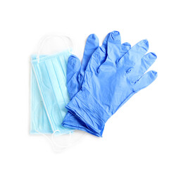 Medical gloves and protective face masks on white background, top view