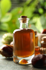 Chestnuts and bottle of essential oil on blue wooden table