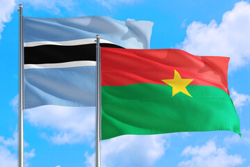 Burkina Faso and Botswana national flag waving in the windy deep blue sky. Diplomacy and international relations concept.
