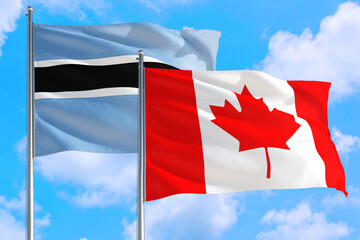 Canada and Botswana national flag waving in the windy deep blue sky. Diplomacy and international relations concept.