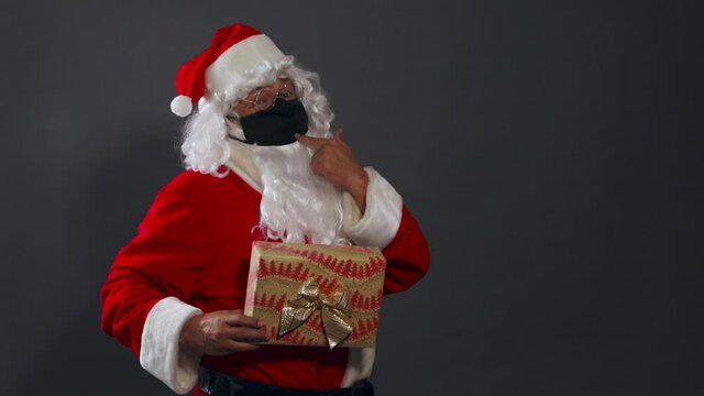 Papa noel con mascarilla pandemia dando regalo mexicano latino