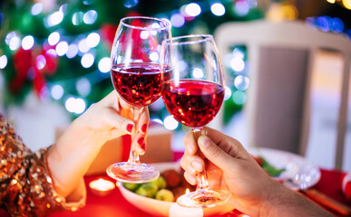 Happy beautiful elegant couple in love are sitting at christmas table and drinks wine from glasses.