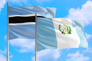 Guatemala and Botswana national flag waving in the windy deep blue sky. Diplomacy and international...