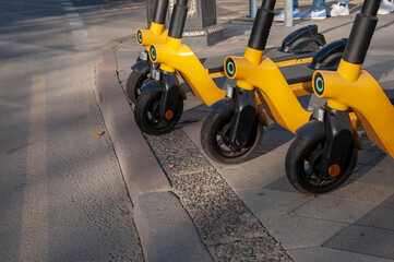 four yellow electric scooters at an intersection on the sidewalk