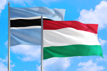 Hungary and Botswana national flag waving in the windy deep blue sky. Diplomacy and international relations concept.