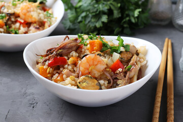 Two plates fried rice with seafood, vegetables, ginger and parsley on dark background. Asian cuisine. Vegetarian food. Closeup. Horizontal format