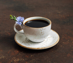 Chicory drink and blue flower on brown background closeup. Natural coffee substitute.