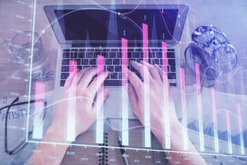 Multi exposure of man's hands typing over computer keyboard and forex graph hologram drawing. Top view. Financial markets concept.